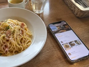 カルボナーラと口コミアプリを表示したスマートフォン